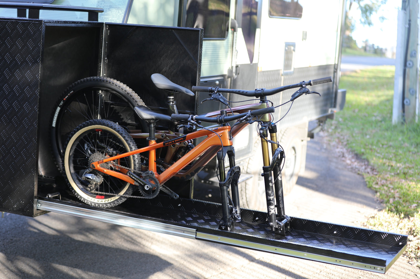 Two mountain bikes on the extended Toysafe slide-out tray beside a caravan